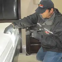 Bed bug inspection technician checking a mattress and bed frame for signs of infestation in Clearwater, FL