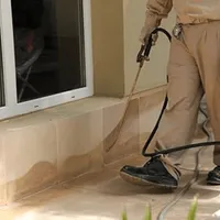 General pest control technician spraying exterior perimeter around a home in Clearwater, FL