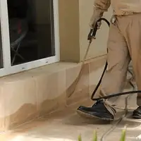 General pest control technician spraying exterior perimeter around a home in Clearwater, FL