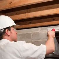 Termite inspection technician checking a basement wall and framing for termite activity in Clearwater, FL