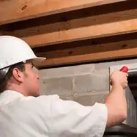 Termite inspection technician checking a basement wall and framing for termite activity in Clearwater, FL